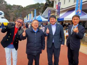 市長と副市長が出店している多くの店を背景に 関係者の方2人と並んで撮影した写真