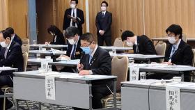 協議会の出席者が自分の名札が張られた机に座っている会場内で、 市長が片手でマイクを持ちながら話をしている写真