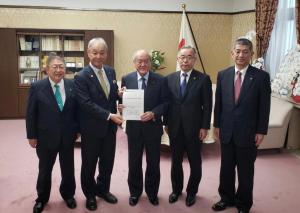 財務省で市長含む関係者5名が並び、中央の男性が要望書を持っている写真