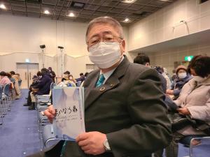 客席に座り「夢かなう扉」のパンフレットを手に持っている市長の写真