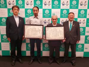 宮古市のバックパネルの前で、それぞれ額入りの賞状を持った畠山さんと大森さんを中央に、市長と副市長が横一列に並んでいる写真