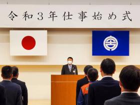 令和3年仕事始め式と書かれた幕の下、演台で市長が参加した職員に向けて式辞を述べている写真