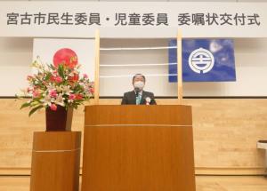 宮古市民生委員・児童委員委嘱状交付式と書かれた横断幕の下で市長が、花台に花が飾られた演台で、式辞を述べている写真