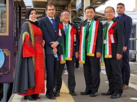 三陸鉄道の駅のフォームでクウェートの国旗の色のマフラーをかけている市長とクウェート国特命全権大使のハサン・モハメッド・ザマーン閣下とマナル・アルシャリーフ大使夫人と市長と同じマフラーをかけている三陸鉄道の関係者の方々が並んで撮影した写真