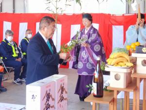 紅白幕で囲まれた安全祈願祭の会場で、榊の枝を持ち玉串奉奠を行っている市長の写真