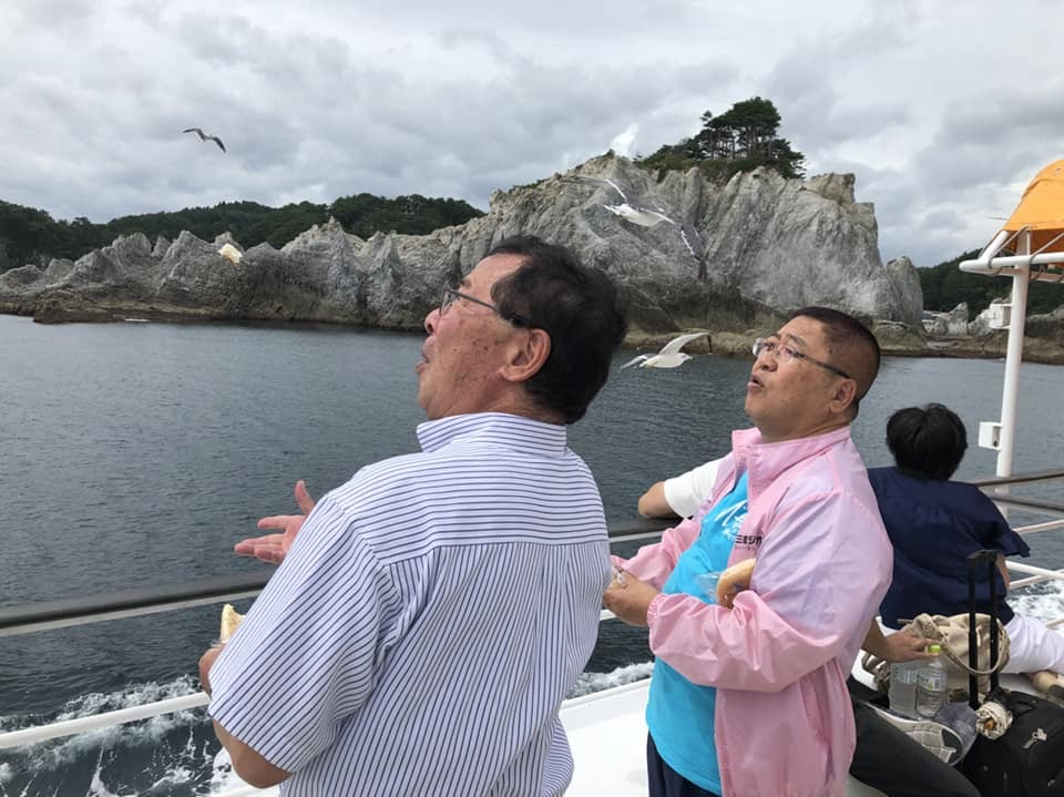 浄土ヶ浜遊覧船に乗り上空を見上げる男性と市長の写真
