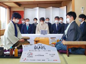 将棋盤を挟んで左側に藤井聡太叡王、右側に菅井竜也八段が正座し向かい合って盤面を見つめ、その奥には屏風の前に立会人の方達が2列になって正座している写真