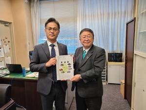 応接椅子が設置された執務室内で、国土交通省の佐々木正士郎道路局次長と市長が一緒に要望書を持ち並んでいる写真
