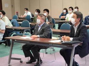 長机が並べられた会場で前方を向き座って話をする様子の市長と参加者たちを写した写真