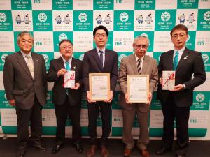 宮古市のバックパネルの前で、中央に株式会社岩手測器社と株式会社鈴木測量設計の担当者の方が額入りの証を持って立ち、それぞれのし袋を持った市長と副市長がと男性の関係者が横一列に並んでいる写真