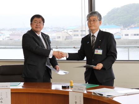 菅原和弘副局長と山本正徳市長が握手をしている写真