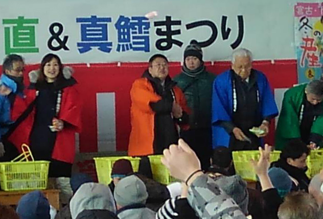法被を着た市長と関係者が、参加者に向けて餅まきをしている写真