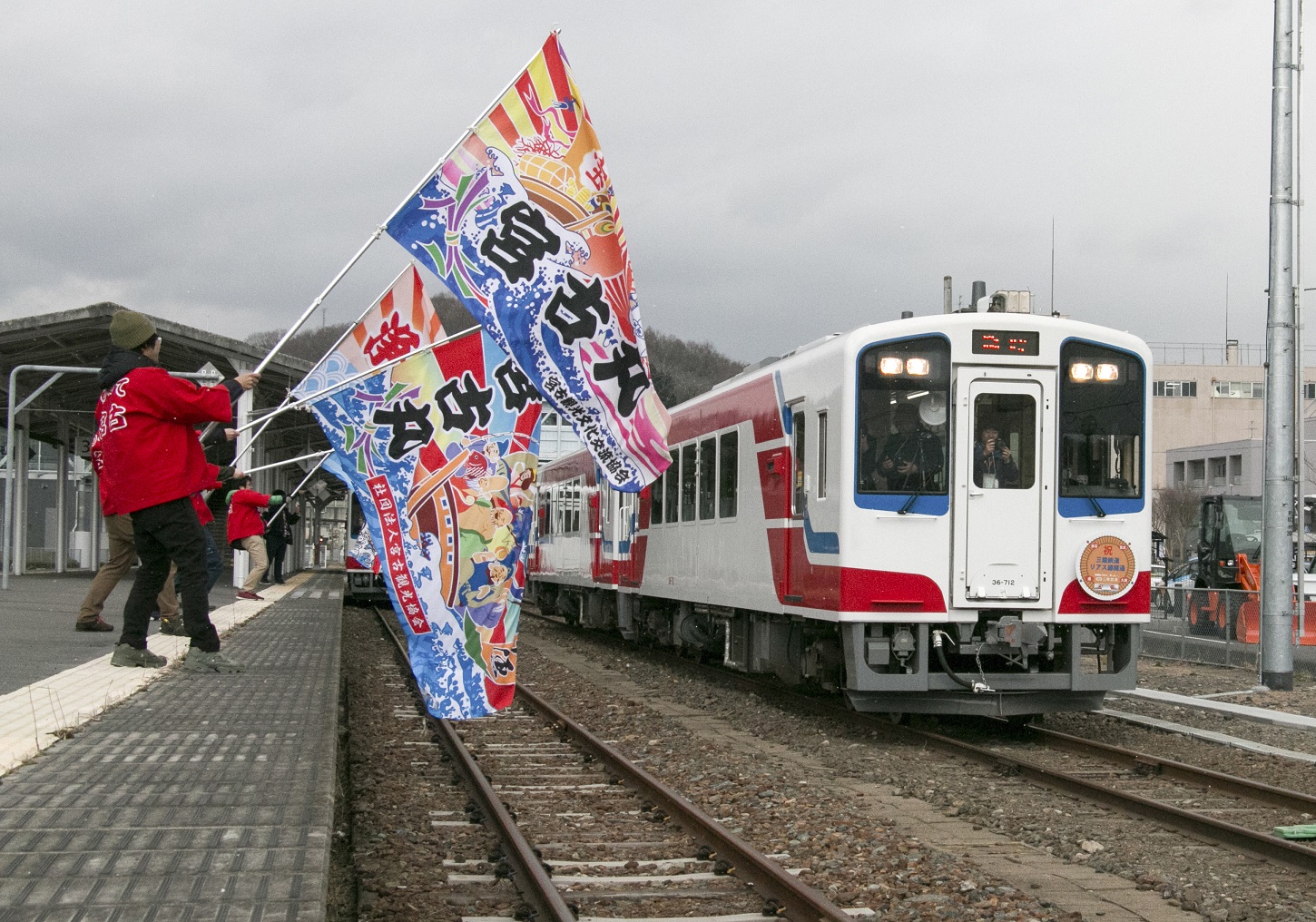 宮古駅のホームに入る車両をカラフルな大漁旗で振りかざしながら、迎えている写真