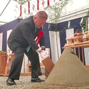 式典にて祭壇の前でスーツを着た市長が、両手に持ったハンマーのようなもので足元にある砂山を崩している写真