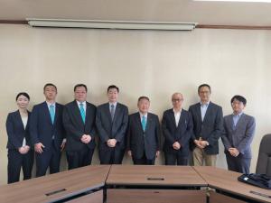 会議室のような場所で中央にいる黒いスーツを着た市長と、その両脇に並んでいるスーツを着た人々の写真