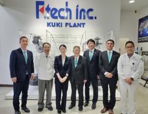 Ftech incと書かれた会社の受付のような場所でスーツを着た市長と、スーツや作業着を着た人々が並んでいる写真