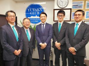 中央に松浦賢太郎代表取締役、同じ水色のネクタイをした宮古市からの訪問者が両脇に2名ずつ並んで記念撮影をしている写真