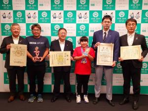 佐々木海寧さんと関係者の計6名が、それぞれが海寧さんが獲得した賞状やトロフィー、メダルを持って並んでいる写真