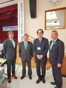 多良間村村制施行110周年記念講演会のステージ下の会場で、仲間勇栄名誉教授と市長に2名の関係者が横一列に並んでいる写真