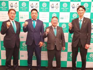 宮古市のバックボードの前で市長を含むスーツ姿の男性4名が右手でガッツポーズをし記念撮影をしている写真
