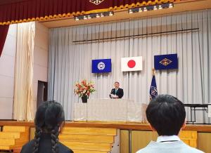 市長が花が飾られたステージ上の演台で、式辞を述べている写真