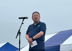 屋外でマイクスタンドの前に立ち話をする市長の写真