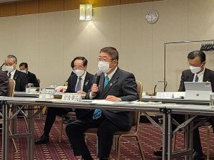 宮古市長と書かれた札が置かれた席に着席した市長が、右手にマイクを持ち話をしている会議の様子の写真