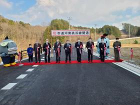 開通した道路にレッドカーペットを引き、その上で、市長と関係者の方々8人でテープカットをした写真