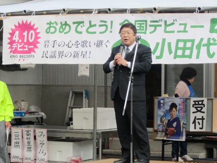 舞台の上でマイクを両手で持ち話をしている様子の市長の写真