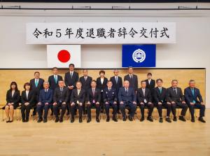 「令和5年度宮古市退職者辞令交付式」の横断幕の前に2列に並んだ男女の退職者の方々と記念撮影をしている写真