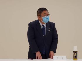 協議会の会場でマスク姿の市長が資料が置かれたテーブルの前に立ち意見を述べている写真
