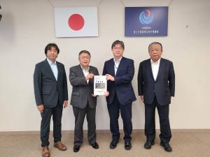 要望書正面に向け一緒に持つ市長とスーツを着た男性、その2人の両端に立つ関係者の男性2名の記念写真