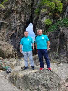 砂浜にある大きな岩の上に立つ青いポロシャツを着た市長と参加者の男性の写真