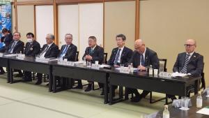 畳の上に長テーブルと椅子が置かれ中央に座り話をしている市長の両脇をスーツ姿の参加者が座り資料を見ながら話を聞いている写真