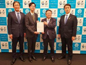 笹原爽志さんと市長で、任命書を持ち、他の職員の方2人と並んで撮影した写真