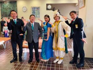 アラジンとランプの魔人の鑑賞で男性2名と市長、アラブの衣装をみにまとったミュージカル出演者2名が右手の平を上に向けて肘を曲げ、左手の平を下に向けながら真下に伸ばした同じポーズをとって記念撮影をしている写真