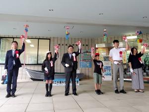 市長を中央に鍬ケ崎小学校の男の子と女の子の2名の生徒、3名の関係者が横一列に並びテープカットが行われた「磯の生物展」のオープニングセレモニーの様子の写真