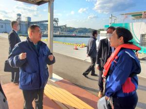 港でオレンジ色のライフジャケットを着た女性と市長が話をしている写真