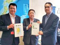 日本地図が壁に貼られた部屋で市長と男性で要望書を持ち、横で別の男性が資料を持っている写真