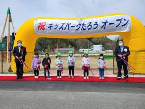 キッズパークたろうオープンと書かれた横断幕が貼られた、空気が入ったゲートの前で市長と道の駅の関係者1人と園児6人で紅白のテープカットした写真