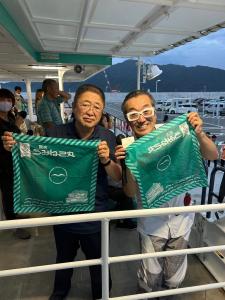 船内でうみねこ丸と書かれた緑意をのハンカチを広げている市長と男性の写真