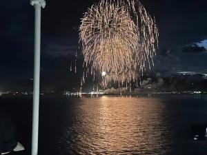 夜空に上がり海に反射する大きな花火の写真