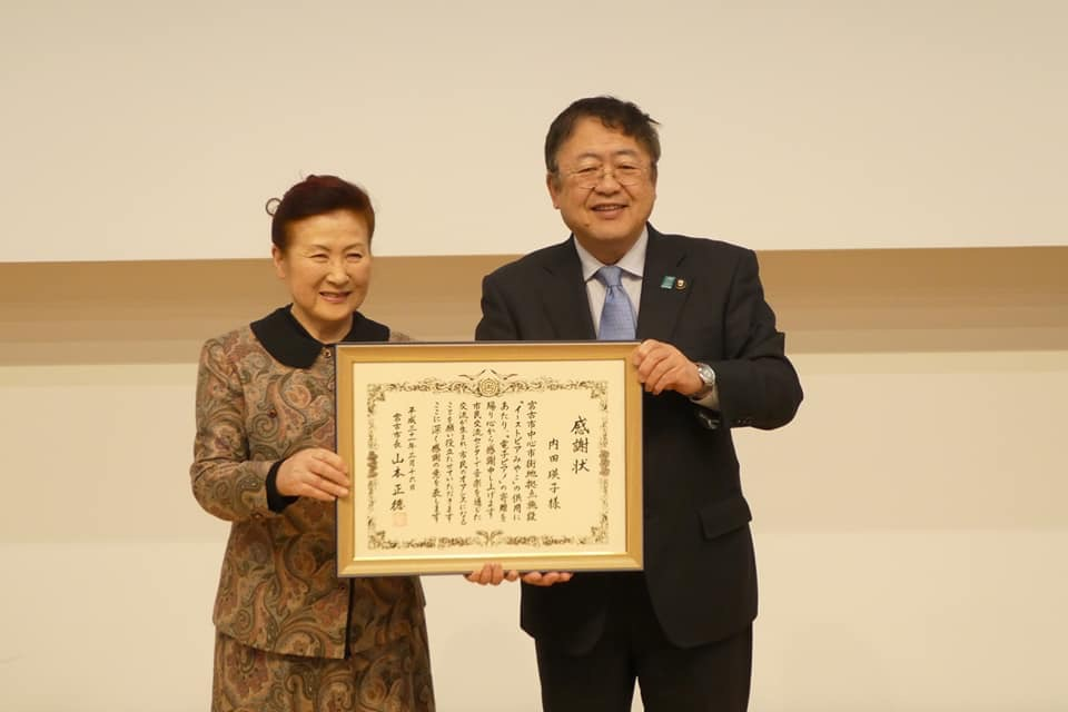 感謝状の額縁を一緒に持つ市長と女性の記念写真