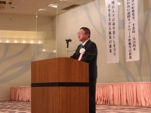 「令和4年度東北国道協議会総決起大会」の檀上に設置されたマイクの前で挨拶を行っている市長の写真