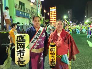 「盛岡市長」と書かれた襷を掛け、同じく「盛岡市長」と書かれた提灯を右手にもつ盛岡市の谷藤市長と、「宮古市役所」と書かれた提灯を持つ山本市長が写った写真