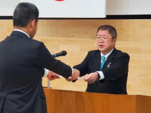 両手で辞令を手渡す市長と受け取る男性の写真
