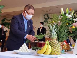 霊鎮祭で花や果物が置かれた祭壇に市長が玉串をささげている写真