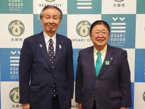 大崎市のバックパネルの前で、吉田大崎副市長と市長が並んで立っている記念写真
