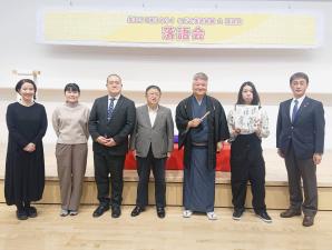 高座台が設置されたステージ上で市長を中央に桂竹丸師匠をはじめ4名の出演者と市の関係者が横一列に並んでいる写真