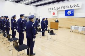 「宮古市交通指導隊初点検式」の横断幕がある室内で、関係者が横並びに起立しており、市長が演壇で話をしている様子の写真